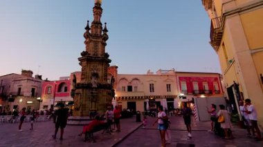 Nardo 'daki Piazza Salandra Meydanı' nda akşam panoramik taraması, batan güneşin zenginleştirdiği kule, Sedile ve yerel atmosferi gözler önüne seriyor.