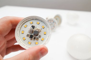 Beyaz arka planda izole edilmiş kırık LED lambayı tutan adam. Kırık beyaz lamba devreleri. Kırık ışık bileşenleri.