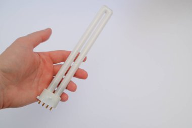 Beyaz arka planda flüoresan ampulü tutan bir adam. - Yakın çekim. Enerji tasarrufu. Bakış açısı atışı. Güç tasarruf kavramı.