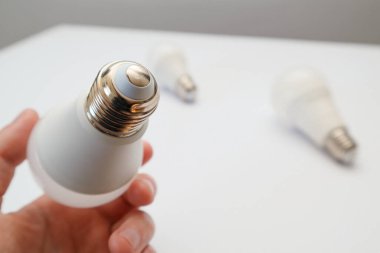 Beyaz arka planda ampulü tutan adam. - Yakın çekim. Enerji tasarrufu. Bakış açısı atışı. Güç tasarruf kavramı.