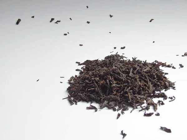 Large dry black tea leaves isolated on white background. Large dry leaves of black tea. Black tea background. Black tea texture.