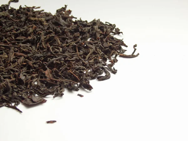 Large dry black tea leaves isolated on white background. Large dry leaves of black tea. Black tea background. Black tea texture.
