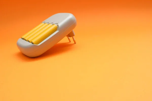 Oplader Batterijen Concept Oplader Met Gele Batterijen Oranje Achtergrond — Stockfoto