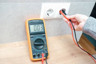 Kadın elektrikçi ev ağındaki voltajı ölçüyor. Elektrik ağlarındaki voltajın ölçümü