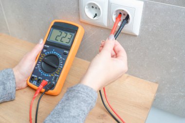 Kadın elektrikçi ev ağındaki voltajı ölçüyor. Elektrik ağlarındaki voltajın ölçümü