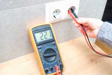 Kadın elektrikçi ev ağındaki voltajı ölçüyor. Elektrik ağlarındaki voltajın ölçümü