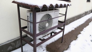 Sıcaklık pompası bir evin duvarına monte edildi ve soğuk bir kış günü karla kaplandı..