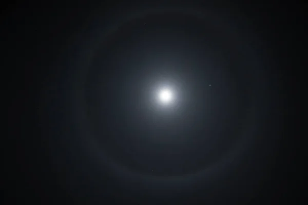 Beautiful winter Halo around the Moon. Super moon with a circular rainbow halo surrounded by stars