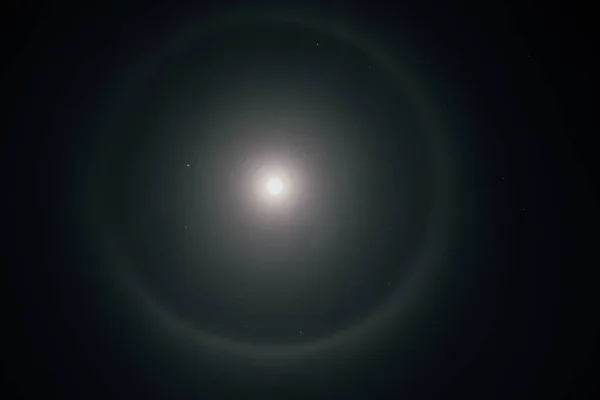 Beautiful winter Halo around the Moon. Super moon with a circular rainbow halo surrounded by stars