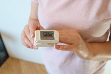 Pulse Oximeter on female hand on white background, measuring blood oxygen level. Portable Oximeter Fingertip tests oxygen saturation