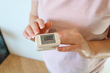 Pulse Oximeter on female hand on white background, measuring blood oxygen level. Portable Oximeter Fingertip tests oxygen saturation
