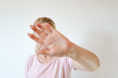 Don't shoot me! Dissatisfied blonde female in shirt showing stop sign with outstretched hand. Negative emotion, facial expression.