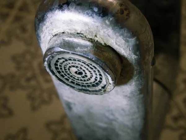 Heavily calcified faucet on a hand basin. Hard water flows from an old tap aerator. Limescale, calcified shower water tap with lime scale in bathroom