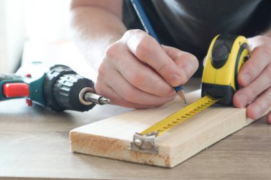 Marangoz, inşaatçı ve boyacı. Ev geliştirme, geliştirme ve onarım için. Ölçüm bandıyla ölçümler yapmak ve kalemle işaretler yapmak. Erkek ellerinin ölçümlerini kapat