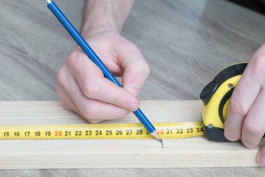 Marangoz, inşaatçı ve boyacı. Ev geliştirme, geliştirme ve onarım için. Ölçüm bandıyla ölçümler yapmak ve kalemle işaretler yapmak. Erkek ellerinin ölçümlerini kapat