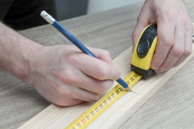 Marangoz, inşaatçı ve boyacı. Ev geliştirme, geliştirme ve onarım için. Ölçüm bandıyla ölçümler yapmak ve kalemle işaretler yapmak. Erkek ellerinin ölçümlerini kapat