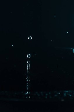 Su sıçrat. Su damlası siyah arkaplana yakın sıçrıyor.