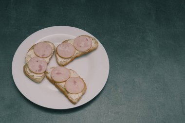 Beyaz tabakta sosisli sandviçler. Dilimlenmiş sosisli sandviç.