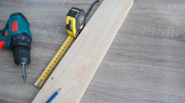 Temel inşaat aletleri ayarlandı. Tahta arka planda elektrikli tornavida kalem ve mezura ölçüsü.