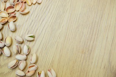 Tahta bir masanın üzerinde fıstık ve ceviz yığını. Fıstık arkaplanı, metin için yer.