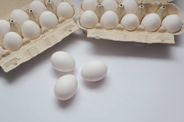 Beyaz masanın üzerinde taze yumurta çiftliği. Beyaz arka planda, kırpma yolu ile izole edilmiş birkaç beyaz yumurta kutusu aç.