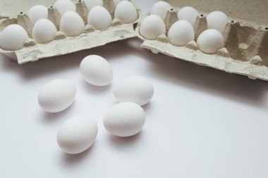 Beyaz masanın üzerinde taze yumurta çiftliği. Beyaz arka planda, kırpma yolu ile izole edilmiş birkaç beyaz yumurta kutusu aç.