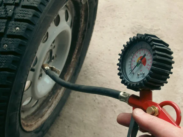 stock image Checking Tire Pressure. Hand holding machine Inflated pressure gauge for car tyre pressure measurement for automobile wheels. Air compressor gun with manometer