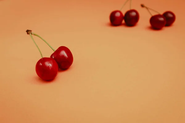 stock image Concept of fresh summer food - delicious cherry. Red sweet cherry berry on a orange background. Cherries. Fresh sweet cherries