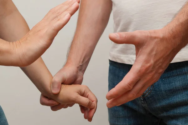 コミュニケーションの問題を持つ若いカップル 暴力行為で女性の手を握っている男 白で隔離された積極的な関係の概念 — ストック写真