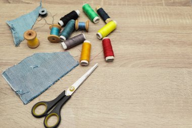 Masada makas ve dikiş malzemeleri var. Ahşap arka plandaki dikiş malzemelerinin tam üstünde. Dikiş için araç ve aksesuarlar