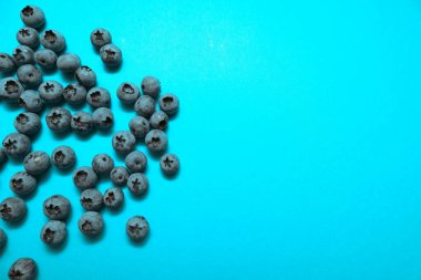 Mavi arka planda olgun yaban mersinleri, metin için yeri olan düz bir yer. Besleyici yaz tatlıları için organik malzemeler.