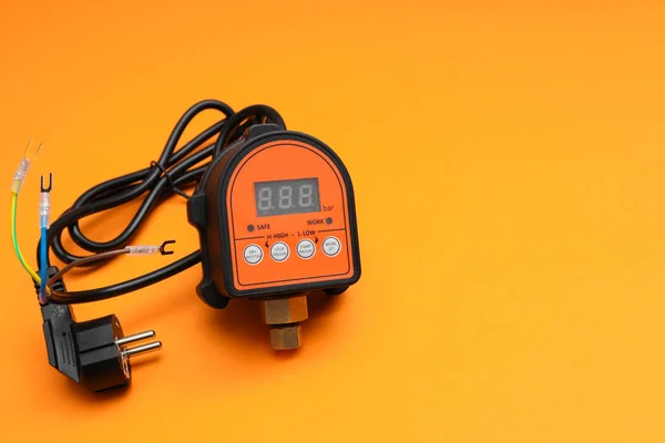 Automatic electronic switch control water pump pressure controller. Automatic water Pump Controller on orange background.