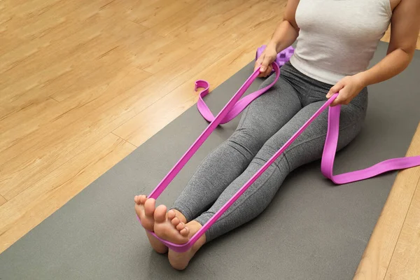 Resistance band exercise at home. Young Female Athlete Exercising with Rubber Tape at Home. Woman doing stretching at home with rubber bands.