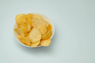 Beyaz arka planda beyaz tabakta patates cipsi..