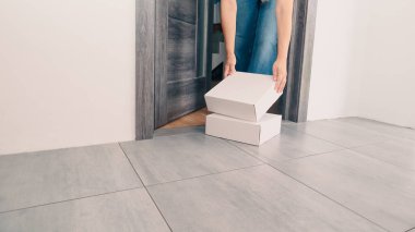 Kadın teslimat paketini evin kapısından alıyor. Kadın paketini evde tutuyor. Teslimat konsepti.