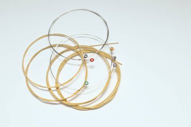 Beyaz arka planda çarpık yeni gitar telleri. Yepyeni akustik gitar telleri. Metin için yer.