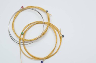 Beyaz arka planda çarpık yeni gitar telleri. Yepyeni akustik gitar telleri. Metin için yer.