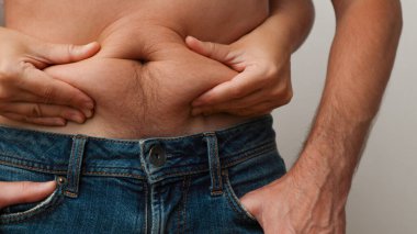 Göbek yağları. Fazla kilolu? Belki bir diyet? Bir kadının elleri, bir erkeğin karnında yağ bağını tutar. Kadının eli onu çok fazla çimdikliyor.