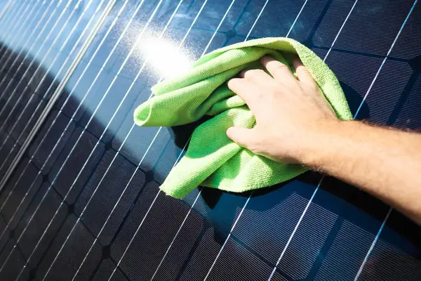 Cleaning solar panel with wipe. Hand wipes solar panels from dirt. Solar panel or photovoltaic module maintenance. Solar power for green energy.