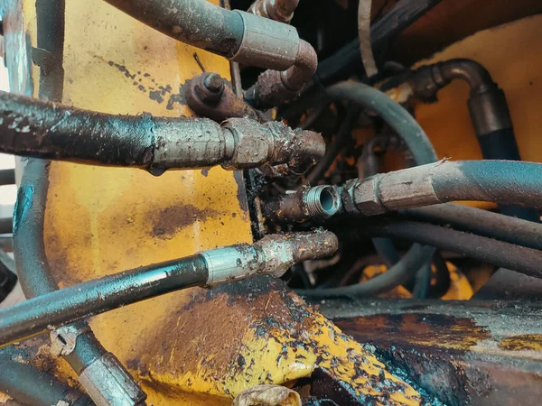 Hydraulic system, steel tubes and rubber parts of lifting mechanism. Details of construction equipment. Close up of pipe system of hydraulic valves in industrial machinery.