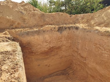 Bir bodrum katı için büyük bir delik. İnşaat alanındaki yeni beton bina inşaatı. Çukur kazıyorum. Özel bir evde inşaat işi