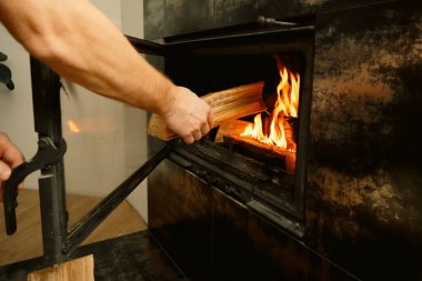 Ev ısıtma konsepti. İnsanlar odunları şömineye elle dolduruyor. Katı yakıt ve ısıtma konsepti