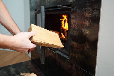 Ev ısıtma konsepti. İnsanlar odunları şömineye elle dolduruyor. Katı yakıt ve ısıtma konsepti