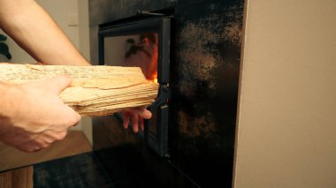 Ev ısıtma konsepti. İnsanlar odunları şömineye elle dolduruyor. Katı yakıt ve ısıtma konsepti