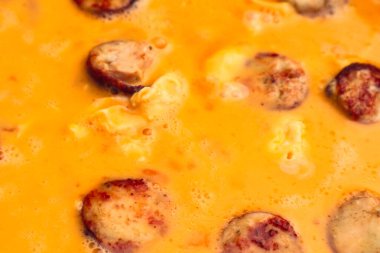 Sosisli omlet yapıyorum. Çırpılmış yumurta için sıvı yumurta kızartma tavasına dökülüyor..