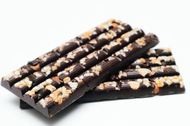 Beyaz arka planda doğranmış fındıklı siyah çikolata, yan görüş. Tatlı yemek. Metin için alanı olan bir model dizayn et.