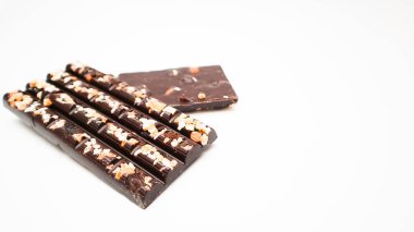 Beyaz arka planda doğranmış fındıklı siyah çikolata, yan görüş. Tatlı yemek. Metin için alanı olan bir model dizayn et.