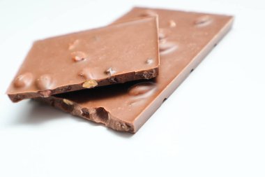 Beyaz arka planda fındıklı sütlü çikolata parçaları. Seçici odaklanma. Bir yığın çikolata.