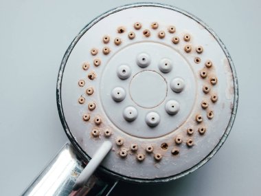 Silver round shower head with hard water deposits, limescales closeup. Calcified shower due to hard water. Selective focus on hard water deposit. clipart