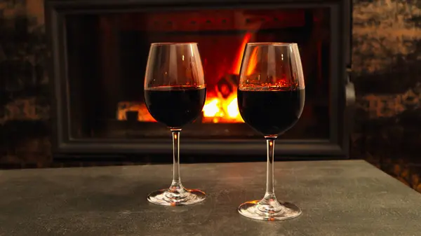 Two glasses of wine near the fireplace in the evening. Red Wine by the Fire